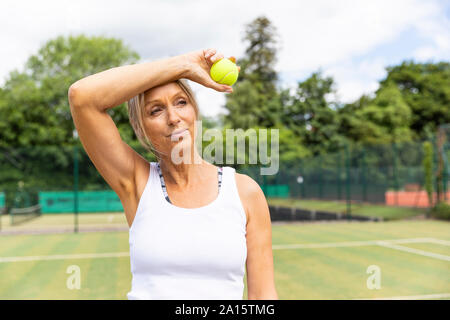 Tired female tennis player taking a break on grass court at tennis club Stock Photo