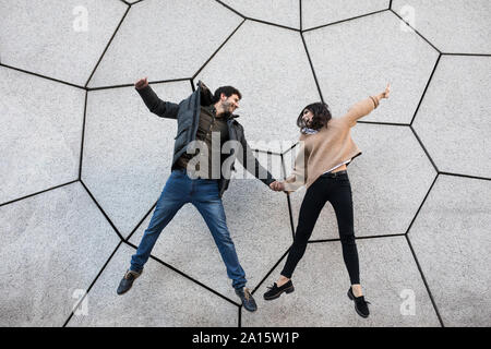 Happy couple jumping in the air looking at each other Stock Photo