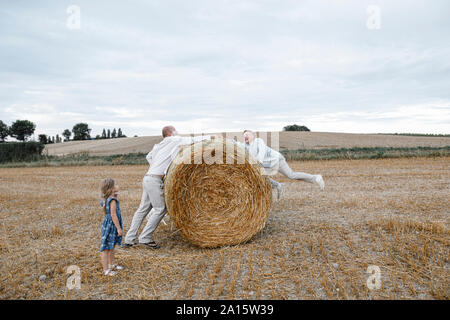 Father and his children playing on hay bales Stock Photo