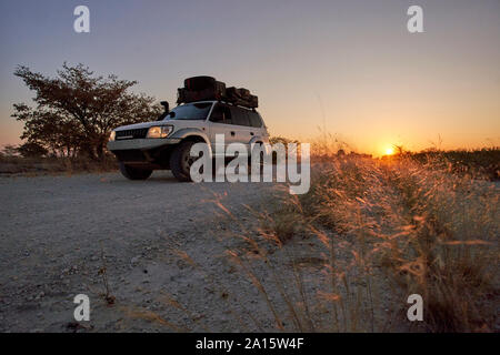 Off-road vehicle driving on a dirt road at sunrise, Makgadikgadi Pans, Botswana Stock Photo