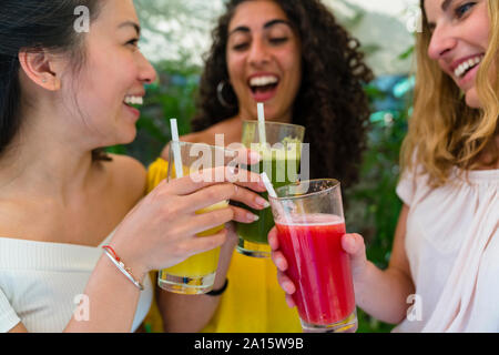 Three happy young women toasting with healthy drinks Stock Photo