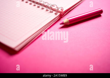 Close up of open notebook and pencil on blurred pink desk Stock Photo