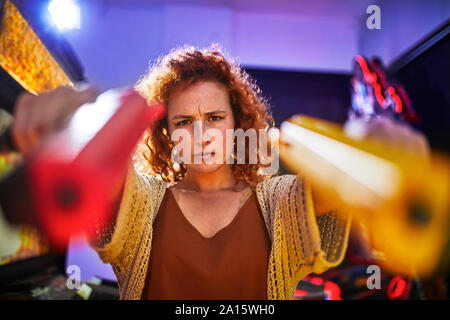 Woman posing and shooting with pistols in an amusement arcade Stock Photo