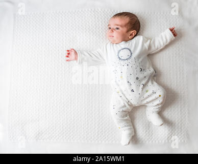 Baby boy laying in bed over white blanket Stock Photo