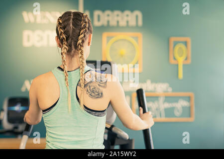 Rear view of young woman exercising on step machine in fitness gym Stock Photo