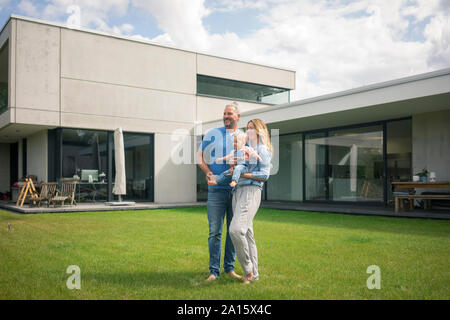 Family of three standing in garden of their home Stock Photo