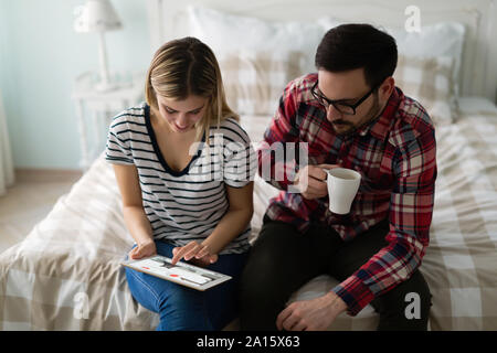 Young attractive couple using tablet in bedroom Stock Photo