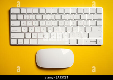 Top view of white computer keyboard and mouse on yellow desk Stock Photo