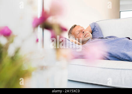 Senior man lying on couch at home taking a nap Stock Photo