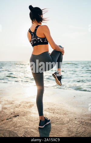 Rear view of a woman stretching her leg on a pier Stock Photo