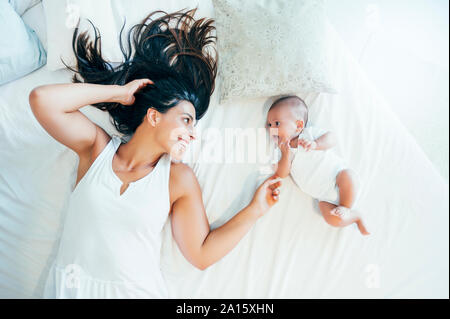 Smiling mother lying in bed with her baby boy Stock Photo