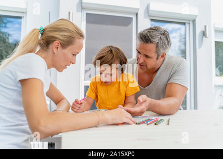 Father, mother and son doing homework together on terrace Stock Photo