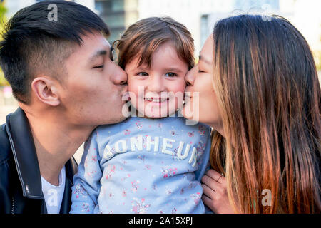 Happy parents kissing little girl Stock Photo