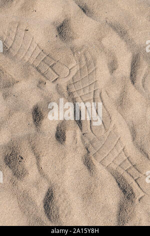 Rather abstract footprints left in beach sand in sunshine. Sunny day at the beach concept. Stock Photo