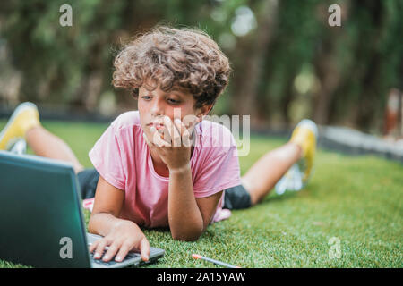 Boy lying in grass using laptop Stock Photo
