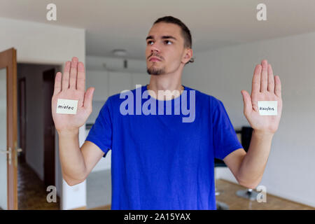 Young man in empty apartment with notes on the palms of his hands Stock Photo