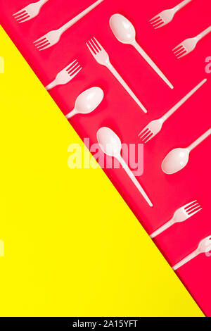 Plastic cutlery, forks, spoons on neon pink background  withe place for text. Recycling concept. Eco problem. Stock Photo