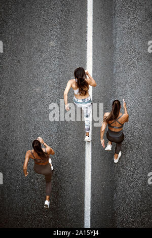 Top view of three sporty young women running on a street Stock Photo