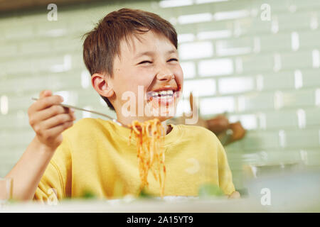 Messy boy eating spaghetti with tomato sauce Stock Photo