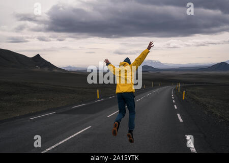 Happy man jumping for joy on an empty road, Iceland Stock Photo