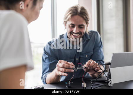 Smiling young man and woman working on computer equipment in office Stock Photo