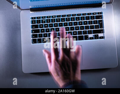 Cyber crime, moving blurred hand typing on a keyboard Stock Photo