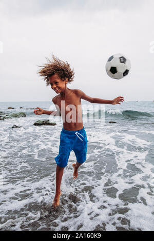 Boy playing with a football on the beach