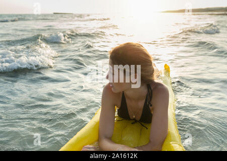 Young woman lying on yellow airbed Stock Photo