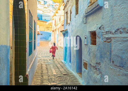 Woman walking in the old city of Chefchaouen with the famous blue buildings, Chefchaouen, Morocco Stock Photo