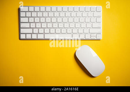 Top view of white computer keyboard and mouse on yellow desk Stock Photo