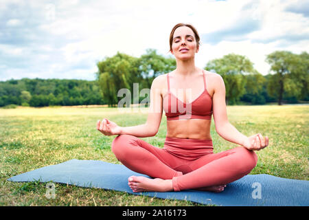 Woman practicing yoga in park meditating