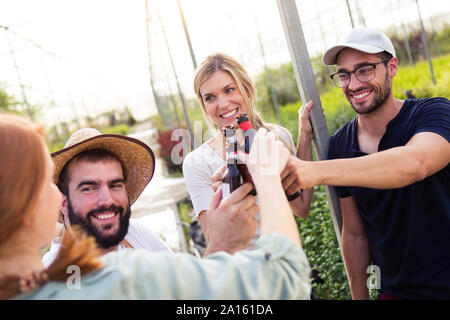 Group of friends toasting with bottles of beer in the greenhouse Stock Photo