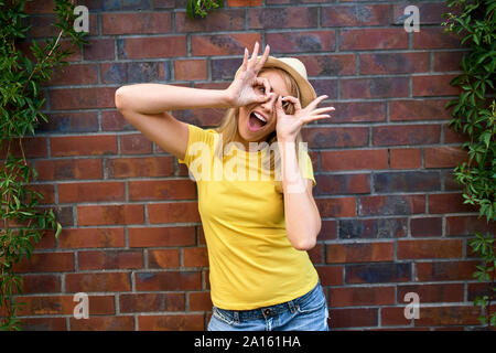 Portrait of playful young woman standing at a brick wall Stock Photo