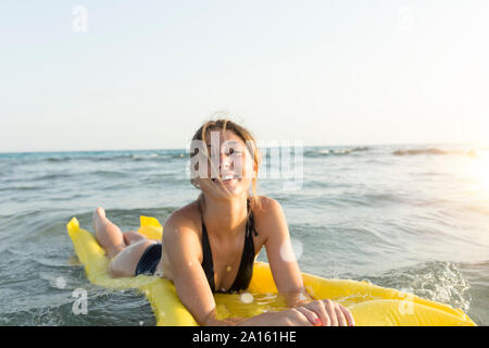 Young woman lying on yellow airbed Stock Photo