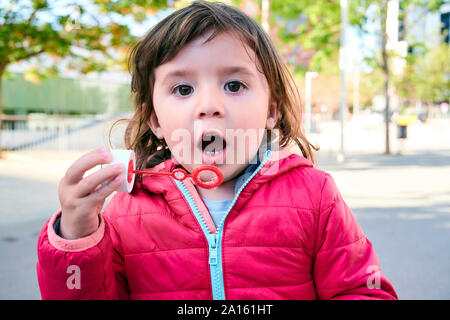 Portrait of little girl making soap bubbles outdoors Stock Photo