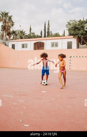 Two children playing soccer on a soccer field Stock Photo