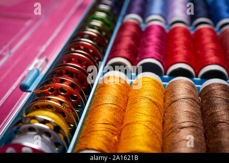 Close up of spools of colored threads in box on pink background Stock Photo