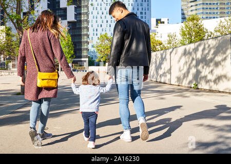 Parents and little girl holding hands and walking together in Barcelona, Spain Stock Photo