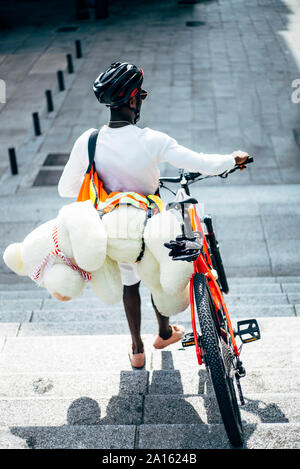 Rear view of bicycle courier delivering a teddy bear Stock Photo