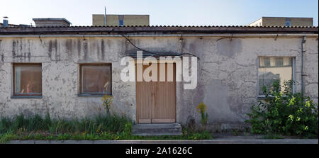 Three rotten curved windows in the yellow plastered  wall of a ruined old brick house. Panoramic collage from several outdoor street photos Stock Photo
