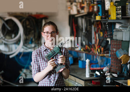 Portrait of confident womanholding drill in her workshop Stock Photo