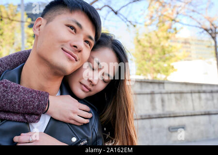 Happy young woman hugging boyfriend outdoors Stock Photo