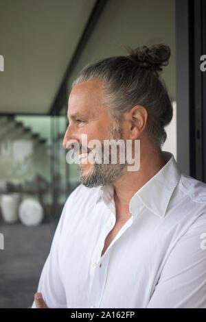 Portrait of happy mature man with hair bun Stock Photo