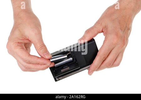 Elderly senior man inserts AA sizes batteries into a portable radio device. Isolated on white studio concept Stock Photo
