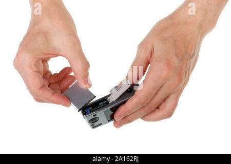 Elderly senior man inserts lithium rechargeable battery  into a conpact photo camera. Isolated on white studio concept Stock Photo