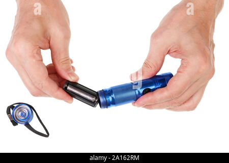 Elderly senior man inserts  AAA sizes  batteries  into a in  LED compact flashlight. Isolated on white studio concept Stock Photo