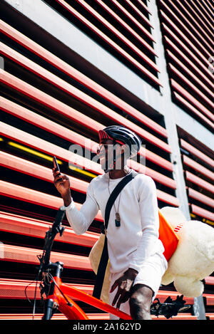 Happy bicycle courier with cell phone and teddy bear Stock Photo