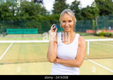 Portrait of smiling mature woman on grass court at tennis club Stock Photo