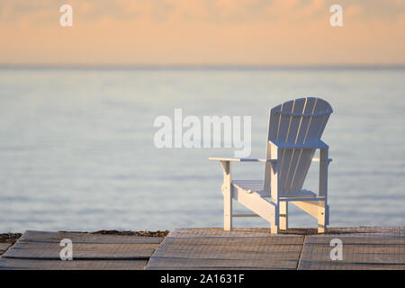 A muskoka chair overlooking Lake Ontario during a warm late-summer sunrise at Toronto, Ontario's Woodbine Beach. Stock Photo