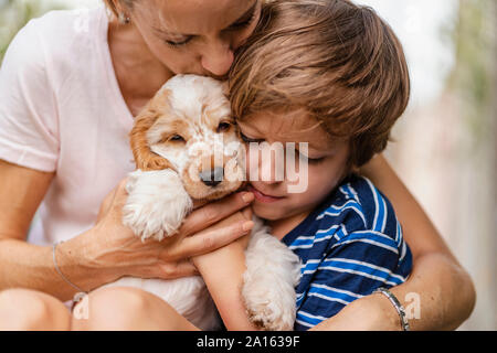 Mother snd son cuddling with cute dog puppy Stock Photo